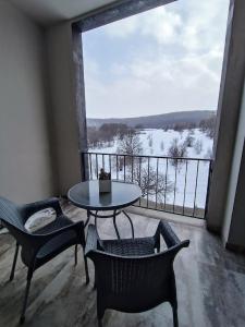 a balcony with a table and chairs and a large window at Sunny apartment in Kechi House, Tsaghkadzor in Tsaghkadzor