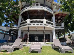 duas cadeiras sentadas na relva em frente a uma casa em Feelgood Whitesand Resort em Lapu Lapu City