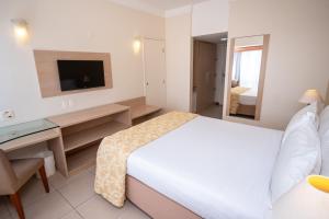 Dormitorio con cama, escritorio y TV en Portobello Ondina Praia, en Salvador