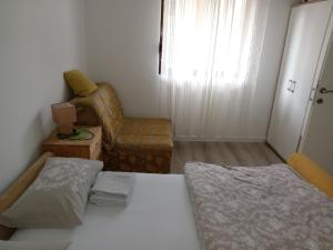 um pequeno quarto com uma cama e uma cadeira em Apartman Mira&Ahmet em Stolac