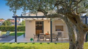 a garden room with a table and chairs next to a tree at Villa Amoroso by Villas Holiday in Nova Vas
