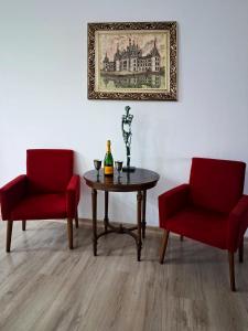 Duas cadeiras vermelhas e uma mesa com uma garrafa. em Galeria Design Art em Florianópolis