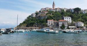 a bunch of boats in the water with a town on a hill at VRBNIK OLD CITY LOFT in Vrbnik