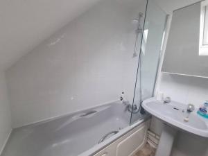 a white bathroom with a tub and a sink at Split level luton town center flat in Luton