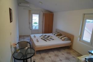 a bedroom with a bed and a chair and a window at Apartments Safija in Dobra Voda