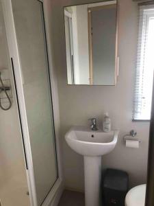 a white bathroom with a sink and a mirror at Luxurious Lodging in Bembridge in Bembridge