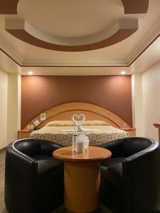 Hotel Gran Vía في مدينة ميكسيكو: غرفة فندقية بسرير وطاولة مع كرسي