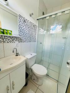 a bathroom with a toilet and a glass shower at Apto no Coração de Serra Negra / 50m da Rodoviaria in Serra Negra