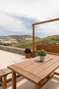 a wooden table on a patio with two potted plants at ĪKADE Mykonos in Mýkonos City