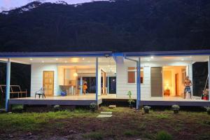una pequeña casa blanca con techo azul en Studio bord de mer Fare Tahitea Pension, en Taputapuapea