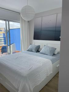 1 dormitorio con cama blanca y ventana grande en Apartamento con vistas al mar Urb Puerto Azul B5, en Cedeira