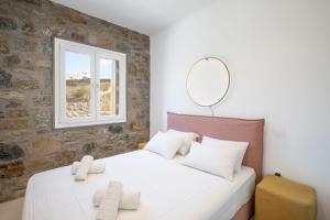 a bedroom with a large white bed with a mirror at ĪKADE Mykonos in Mýkonos City