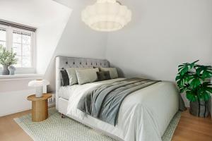 a white bedroom with a bed and a potted plant at Central beautiful modern accommodation near Stockholm City in Stockholm