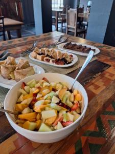 eine Schale Obst auf einem Tisch mit Teller mit Lebensmitteln in der Unterkunft El Paraíso Arroyito in Arroyito