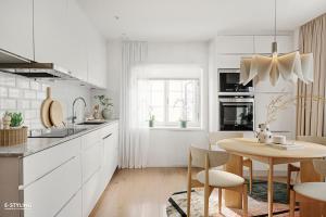 a kitchen with white cabinets and a wooden table at Central beautiful modern accommodation near Stockholm City in Stockholm