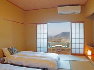 a bedroom with a bed and a balcony with a table and chairs at Aso Canyon Terrace & Lodge in Minami Aso