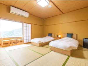 a bedroom with two beds and a large window at Aso Canyon Terrace & Lodge in Minami Aso