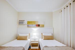 Duas camas num quarto com paredes brancas em Roomo Residencial Itaim Bibi by Transamérica em São Paulo