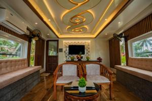 a living room with two chairs and a coffered ceiling at Alice Houseboats Alleppey in Alleppey