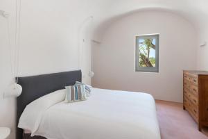 - une chambre avec un lit blanc et une commode en bois dans l'établissement Masseria Pensato, à Savelletri di Fasano