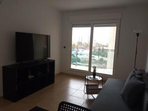 uma sala de estar com uma televisão de ecrã plano e um sofá em VENEZIOLA TRAVEL, relax & beach em La Manga del Mar Menor