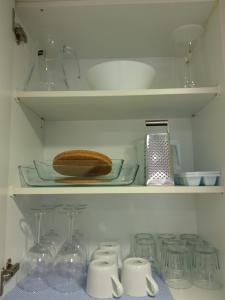 - une étagère avec de la vaisselle, des bols et des verres dans un réfrigérateur dans l'établissement VENEZIOLA TRAVEL, relax & beach, à La Manga del Mar Meno