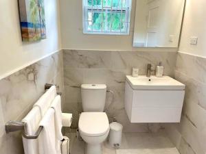 a white bathroom with a toilet and a sink at Modern 1 Bedroom Apartment - 3 min walk to beach in Saint James