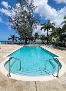 a large swimming pool with palm trees and the ocean at Modern 1 Bedroom Apartment - 3 min walk to beach in Saint James