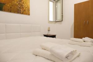 a white bedroom with white towels on a bed at La perla del mare in Trapani