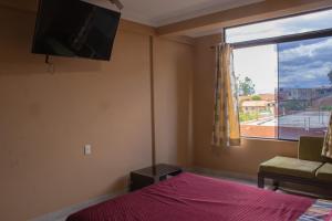 a bedroom with a bed and a tv and a window at Residencial Tablada in Tarija