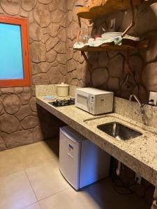 a kitchen with a sink and a microwave on a counter at Refúgio Ecológico Pedra Afiada in Praia Grande