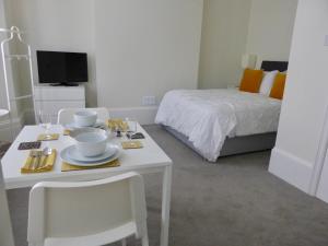 Pokój z łóżkiem oraz białym stołem i krzesłami w obiekcie Stylish studio apartment in central Hove. w Brighton and Hove