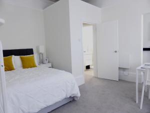 Biała sypialnia z białym łóżkiem i biurkiem w obiekcie Stylish studio apartment in central Hove. w Brighton and Hove