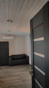 une chambre avec un canapé noir et une porte dans l'établissement Gravas mala, à Sigulda