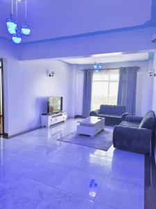 ein Wohnzimmer mit blauer Decke, Sofa und TV in der Unterkunft 2 Bedroom in Kilimani in Nairobi
