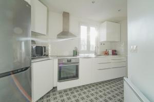 uma cozinha com armários brancos e um forno com placa de fogão em Quiet cosy and large apartment with Terrace Top location em Saint-Ouen