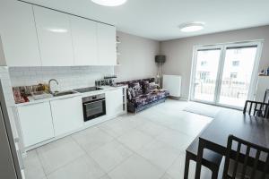 a kitchen with white cabinets and a table and a dining room at Apartamenty Bokserska in Warsaw