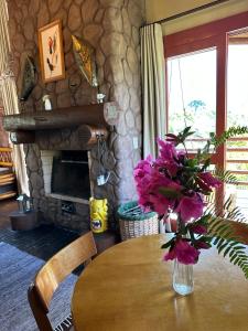 a table with a vase of purple flowers on it at Refúgio Ecológico Pedra Afiada in Praia Grande