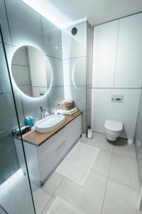 W łazience znajduje się umywalka, lustro i toaleta. w obiekcie Apartamenty Bokserska w Warszawie