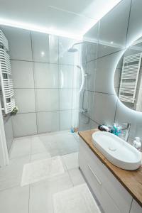 biała łazienka z umywalką i prysznicem w obiekcie Apartamenty Bokserska w Warszawie