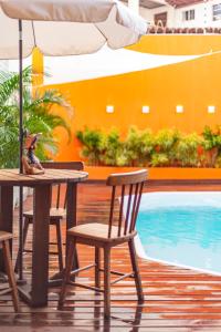 una mesa con sillas y una sombrilla junto a la piscina en Valencia Hotel Natal, en Natal