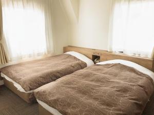 dwa łóżka w pokoju z dwoma oknami w obiekcie Ichinomiya Green Hotel w mieście Ichinomiya