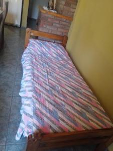uma cama de madeira com um cobertor colorido em Triana alquiler de casa para turista em San Rafael