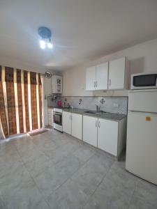 a kitchen with white cabinets and a white refrigerator at Tantanakuy in Villa General Belgrano