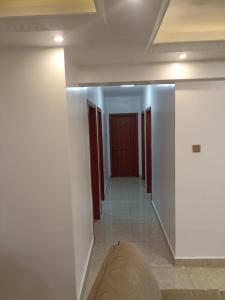 a hallway with white walls and a red door at Home Croft Nairobi in Nairobi
