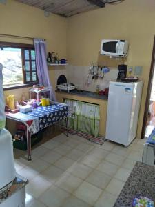 Il comprend une cuisine équipée d'une table et d'un réfrigérateur blanc. dans l'établissement Por do sol Jaguanum, à Mangaratiba