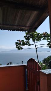 - une vue sur l'océan depuis une maison avec un arbre dans l'établissement Por do sol Jaguanum, à Mangaratiba