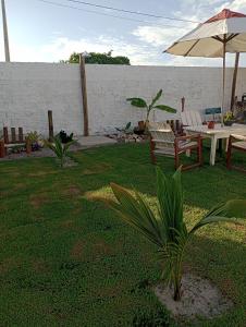 un patio con mesa, sillas y sombrilla en Vida Gostosa Pousada, en São Miguel do Gostoso