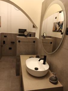 ein Bad mit einem Waschbecken und einem Spiegel in der Unterkunft Domos Le Due Tuie in Piscinas