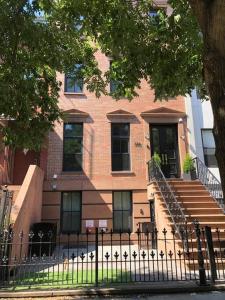 a brick building with stairs and a fence at Private Street Level Brownstone Apartment in Brooklyn